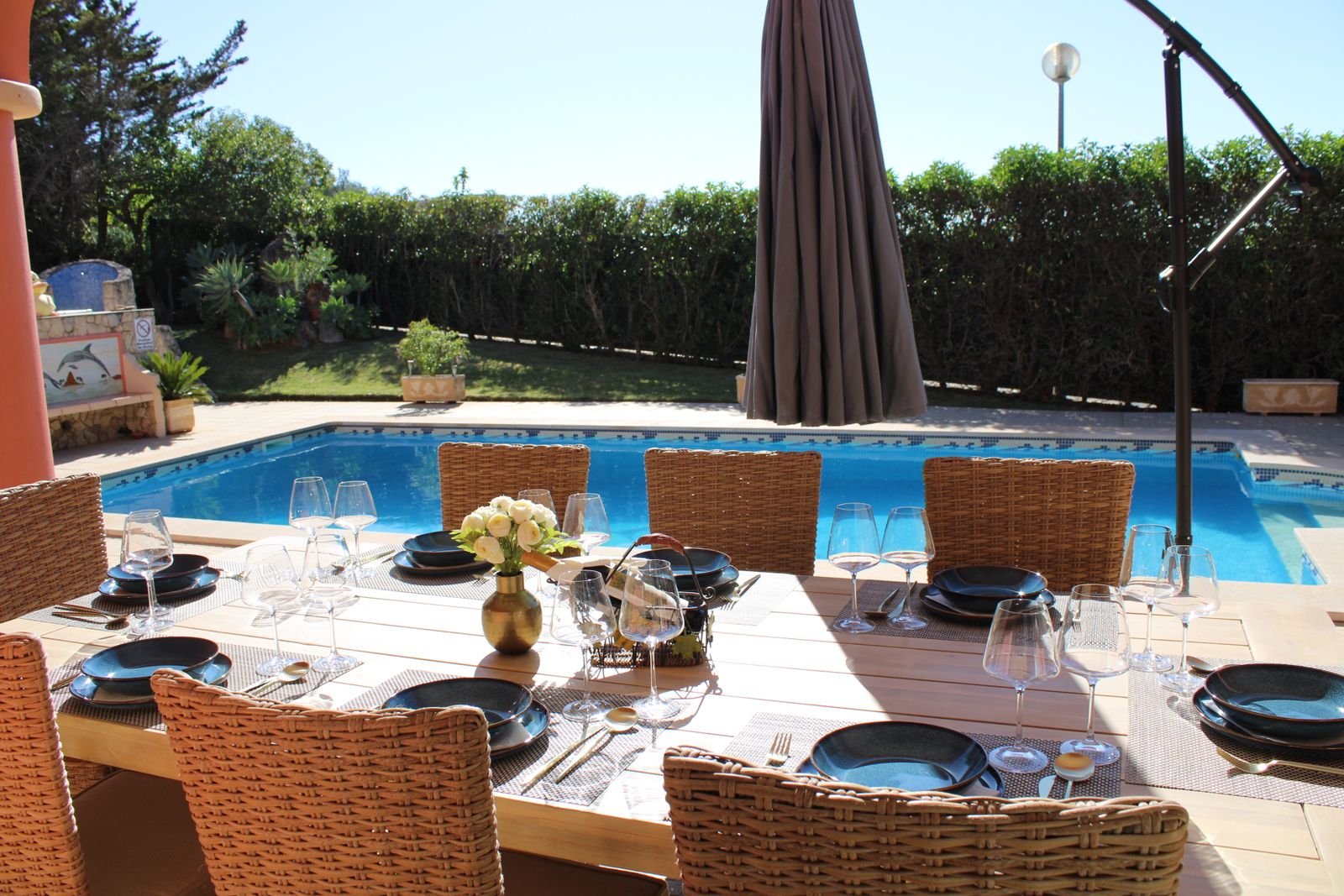 Outdoor dining table set for dinner beside the pool